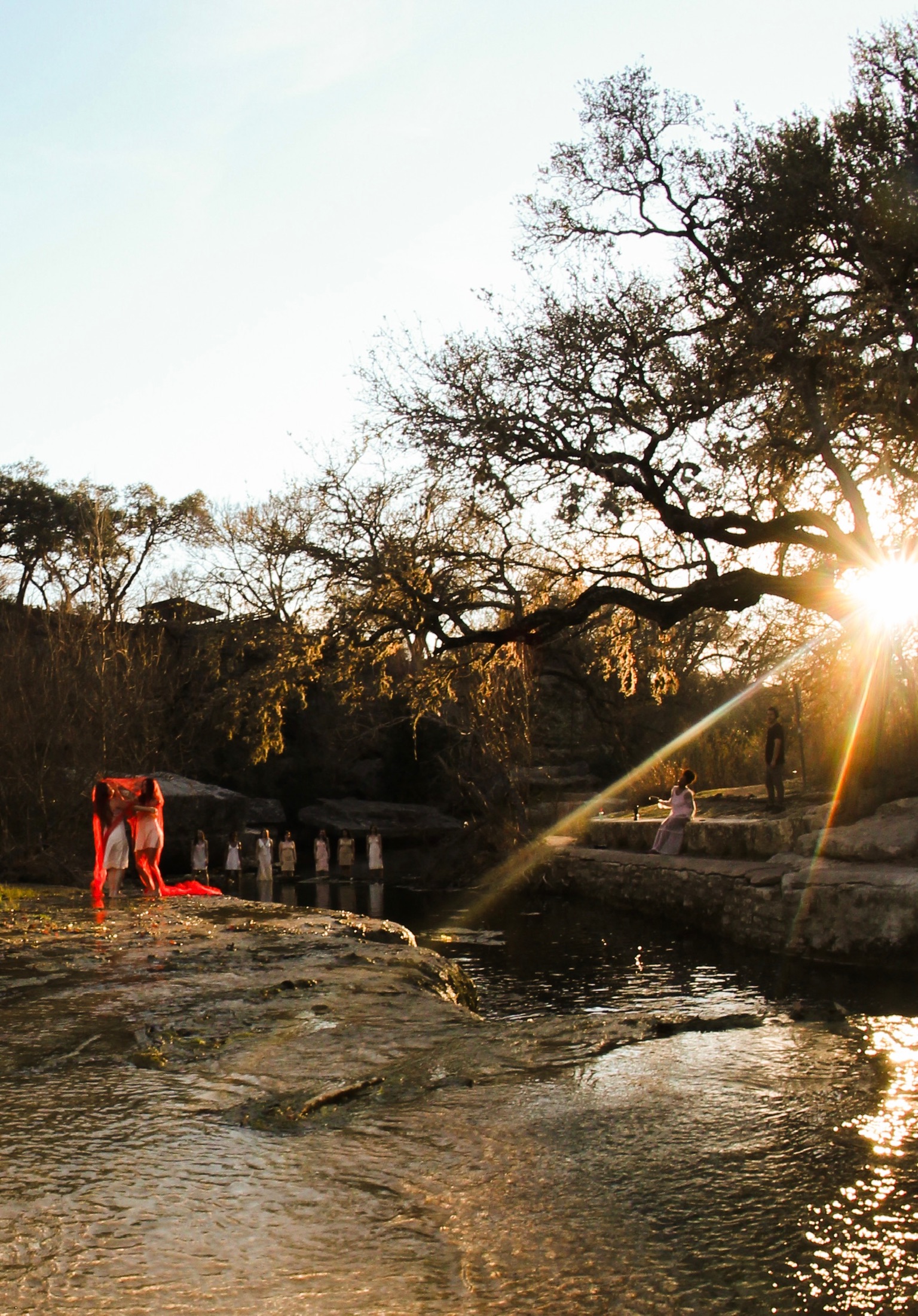 Dancers in white slips standing in the creek at golden hour