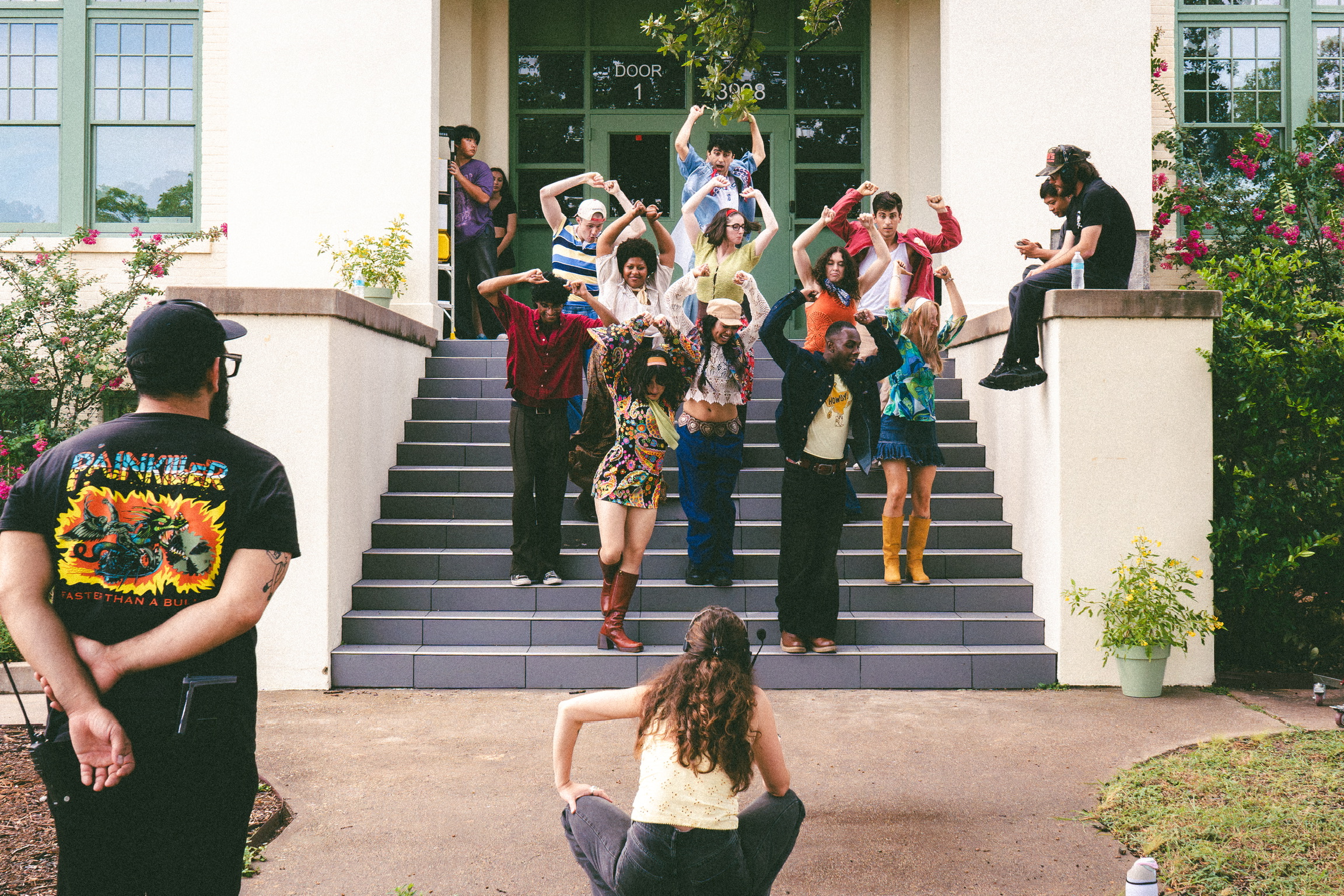 The cast rehearsing choreography on the school steps between takes